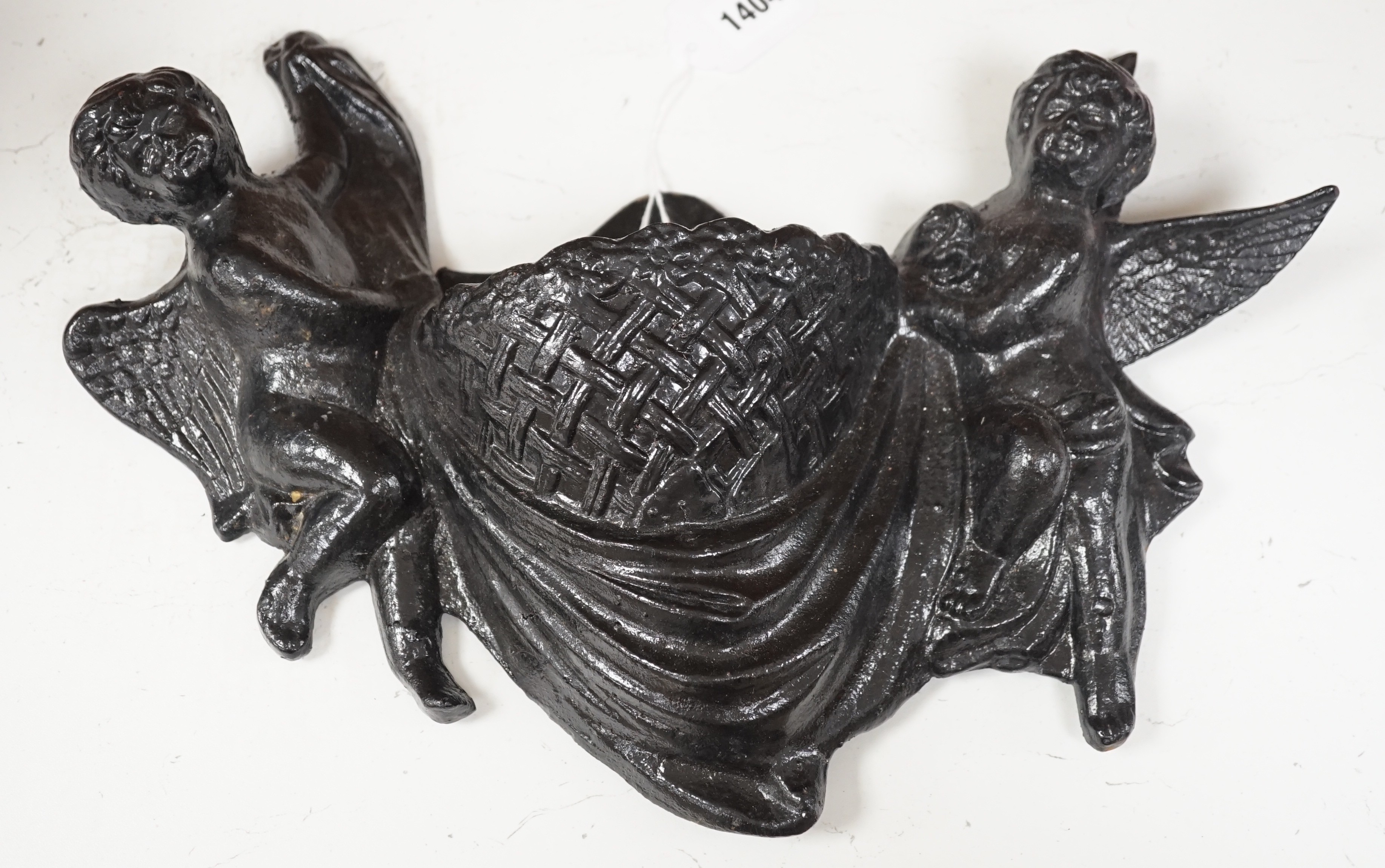 A black painted cast iron cherub flower wall bracket. 40cm wide